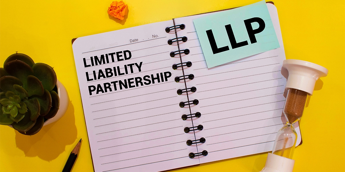 Notebook with LLP text and timer on desk symbolising time-sensitive decisions on LLP benefits and disadvantages.