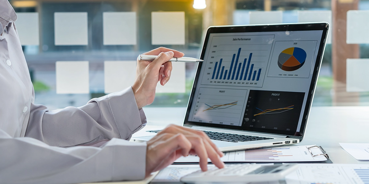 Business professional reviewing graphs and charts on a laptop to assess the financial benefits of forecasting accurately.