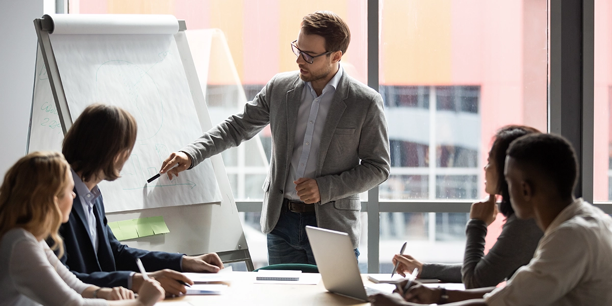 A business trainer presenting to a group of professionals at a meeting, illustrating the concept of CEO development.