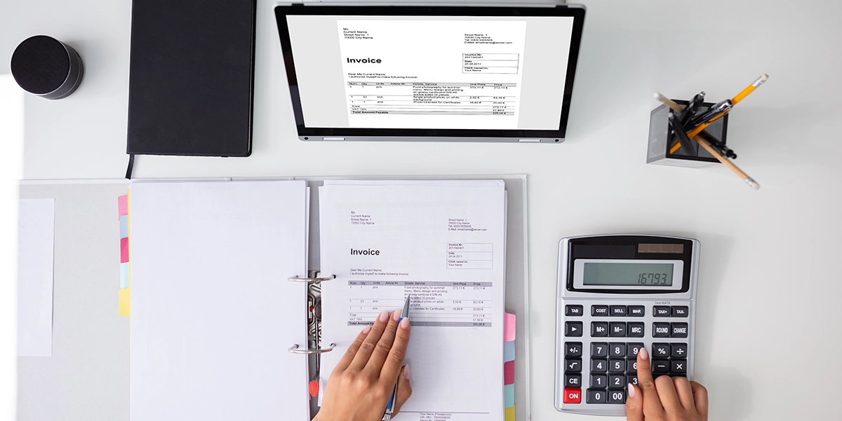 Businessperson reviewing invoices and using calculator, representing careful financial planning for startup funding.