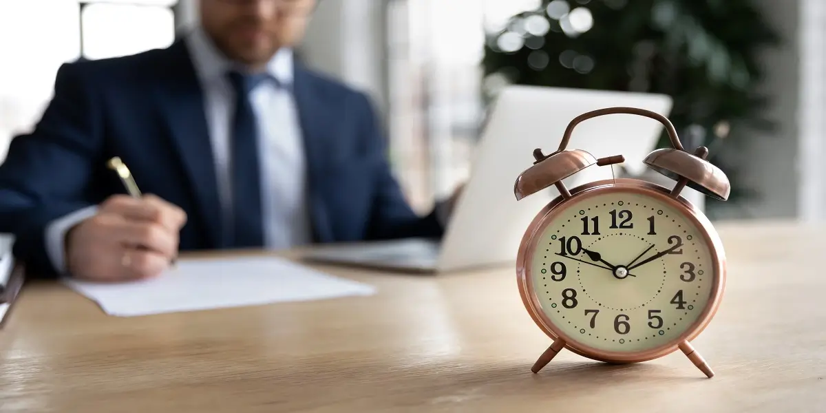 Businessman working at desk with clock in focus, symbolising urgency around HMRC investigation time limits.