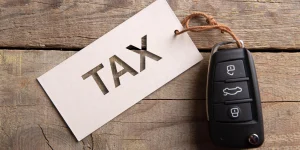 UK vehicle excise duty concept with car key and tag labelled tax on wooden table representing road tax payments for vehicle owners in the UK