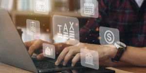 Person typing on a laptop with digital tax icons floating, symbolizing the transition to digital tax reporting under MTD for Income Tax.